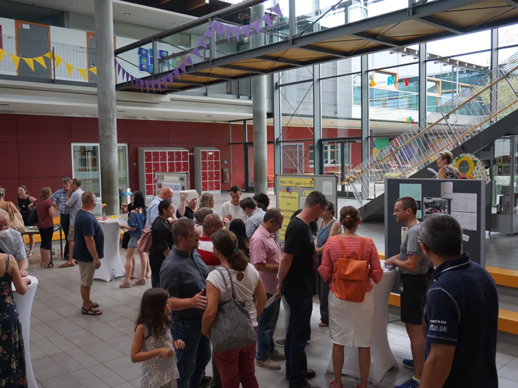 Belebtes Foyer mit Wimpelketten und vielen Gästen.